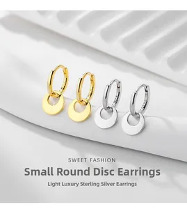 Close-up of 925 sterling silver hoop earrings with round disk pendants in gold and silver