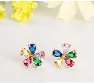 Macro view of flower-shaped stud earrings with colorful zircons in rose gold base