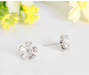 Detailed macro view of small flower-shaped copper earrings with inlaid zircon stones