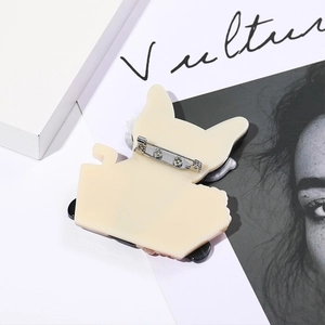 Detail view of the silver metal pin clasp on the back of a cartoon acrylic puppy brooch