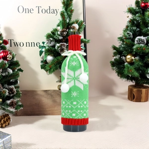 Detail der gestrickten Weihnachts-Weinflaschenhülle mit Schneeflockenmuster und Bommelschleife