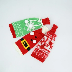 Detail der gestrickten Weihnachtsweinflaschenhüllen mit Schneeflocken und Bommeln