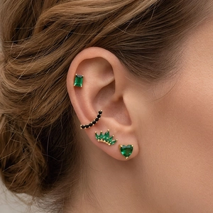18K gold plated stud earrings set with emerald green zircons on a female model's ear