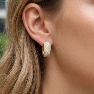 Close-up of elegant gold hexagonal hoop earrings with micro-pave crystals on model