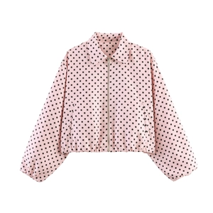 Close-up of pink bomber jacket with black polka dots featuring zipper and ruffled hem