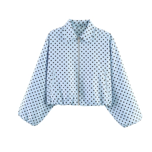 Detailed close-up of light blue polka dot bomber jacket with metal zipper and elastic hem