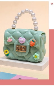 Detail of mint green mini silicone bag with quilted pattern and cartoon charms