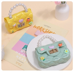 Detailed view of mini jelly purses in yellow and mint green with pearl handles and charms
