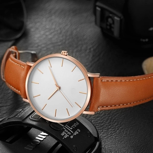 Macro detail of white dial and rose gold case on brown leather strap men's watch