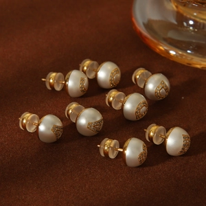 Macro view of vintage pearl earrings with gold letter accents and sparkly crystals