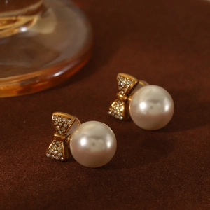 Macro shot of vintage gold bow earrings with sparkling pavé stones and white pearls