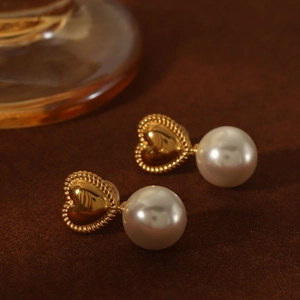 French vintage gold heart earrings with elegant large white pearls on textured background
