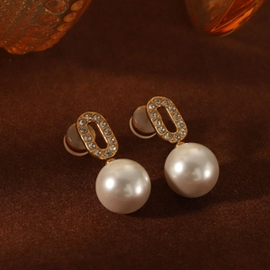 Detailed close-up of retro pearl earrings with crystal inlay on brown matte surface
