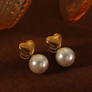 Detailed close-up of vintage heart-shaped gold studs with elegant round pearls