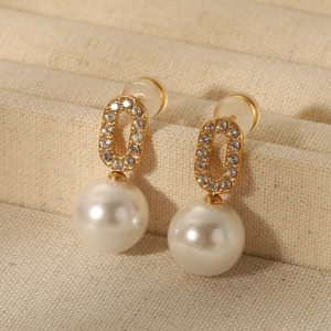 Close-up of vintage gold pearl earrings with shimmering crystals on a jewelry tray