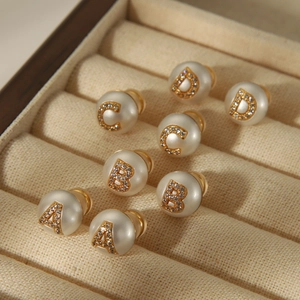 Close-up of vintage pearl stud earrings with crystal-encrusted A, B, C, D letters