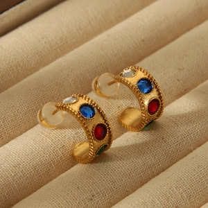 Detailed macro view of gold C-shaped earrings with multi-colored gemstone inlays