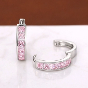 Macro shot of silver earrings with princess-cut pink cubic zirconia in channel setting