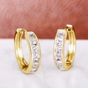 Macro shot of gold hoop earrings with square-cut clear zircon stones in a channel setting
