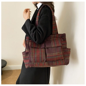 Detail view of large red and green plaid tote bag with functional pockets and wool fabric