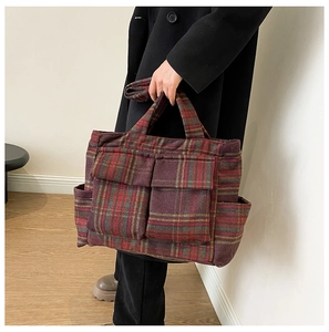 Detail of checkered plush tote bag with functional utility pockets and long shoulder strap