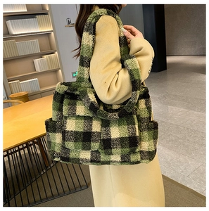 Detail of a large fuzzy green plaid tote bag carried by a model in a cozy winter setting