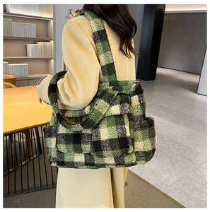 Model wearing a green and black checkered plush tote bag over a beige coat