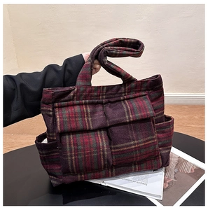 Detail of red and green plaid plush tote bag with functional front pockets and soft texture