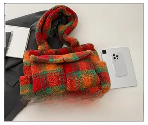 Detailed close-up of a plush plaid tote bag with red and orange tartan pattern and soft fleece
