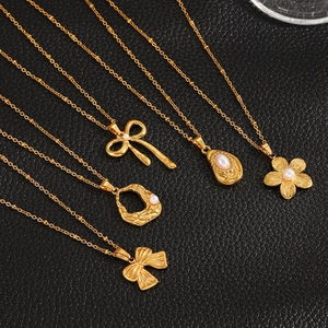 Detailed macro view of five gold-plated bow and pearl necklaces on black leather