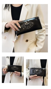 Detail of glossy black skull clutch wallet with silver vintage metal corners and studs