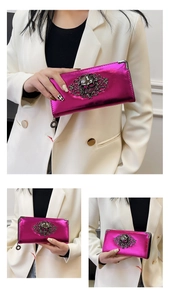 Three-view detail of glossy magenta long wallet with skull and floral metal relief