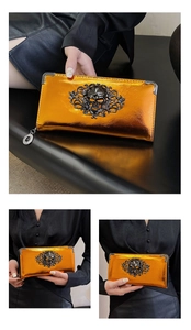 Detail of glossy metallic orange gothic skull wallet with embossed vine patterns and charms