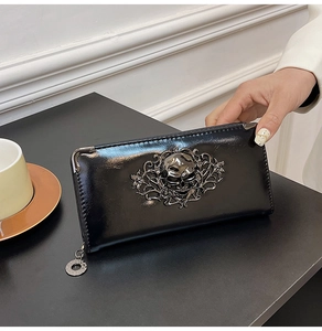 Detail of glossy black skull wallet featuring intricate metal rose vine and corner protectors