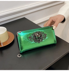 Close-up of metallic green skull wallet with vintage ornate patterns and metal zipper