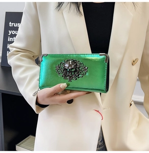 Detail of green metallic skull clutch bag with ornate black vine gothic ornament