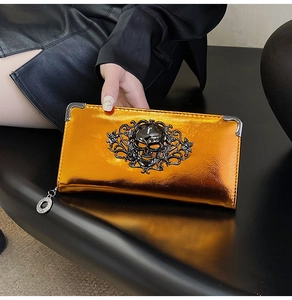 Detail of bright orange metallic wallet featuring a skull relief and silver corners