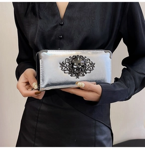 Close-up of a silver skull clutch bag featuring intricate metal corners and gothic patterns