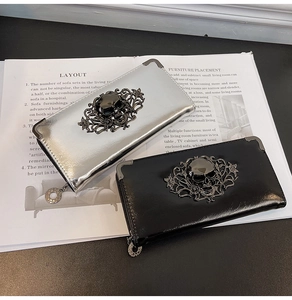 Detail of gothic skull wallets in silver and black with embossed floral vine patterns