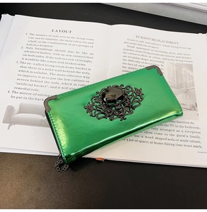 Detail of green metallic skull embossed long zipper wallet on a fashion magazine