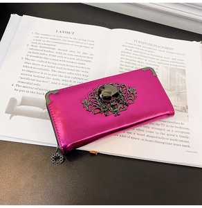 Macro view of metallic magenta long wallet with gothic skull and floral metal relief