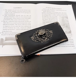 Close-up of black glossy long wallet with metal skull relief and ornate corner protectors
