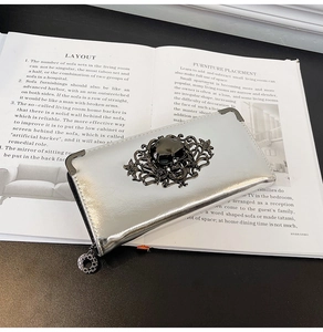 Macro shot of silver metallic wallet featuring black skull relief and ornate scrollwork