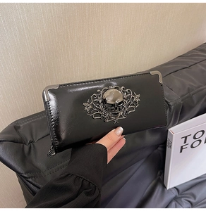 Detail of black long wallet with metal skull relief and reinforced corners for women