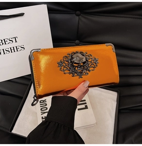 Detail of glossy orange punk wallet with metallic skull relief and silver metal corners