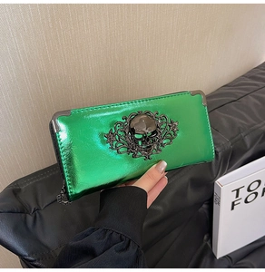 Macro detail of glossy emerald green long wallet with large skull metal ornament