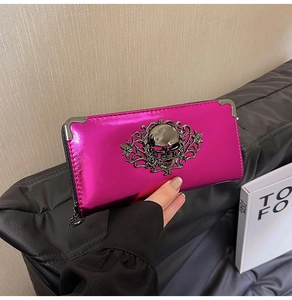 Macro shot of metallic fuchsia wallet featuring an embossed skull and filigree metal ornaments