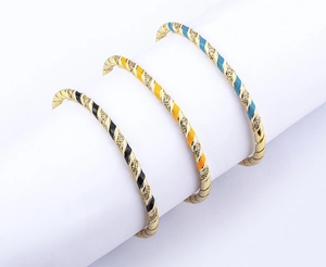 Macro shot of 18k gold plated twisted cuff bracelets with colorful enamel and zircon stones