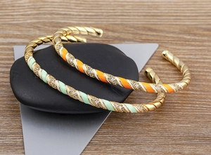 Detail of twisted 18k gold plated cuff bracelet with colorful enamel and zircon stones