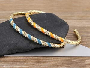Detailed macro of 18k gold plated bohemian cuff bangles with colorful enamel check pattern